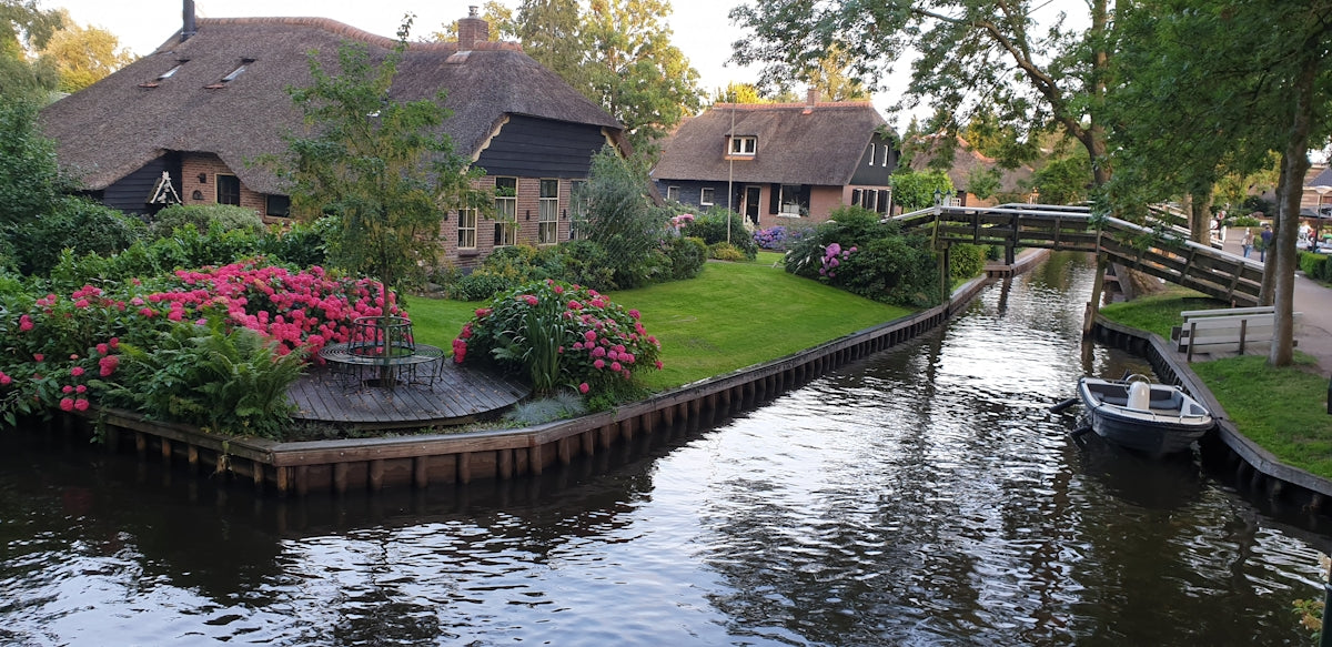 a boat traveling down a river next to a lush green field