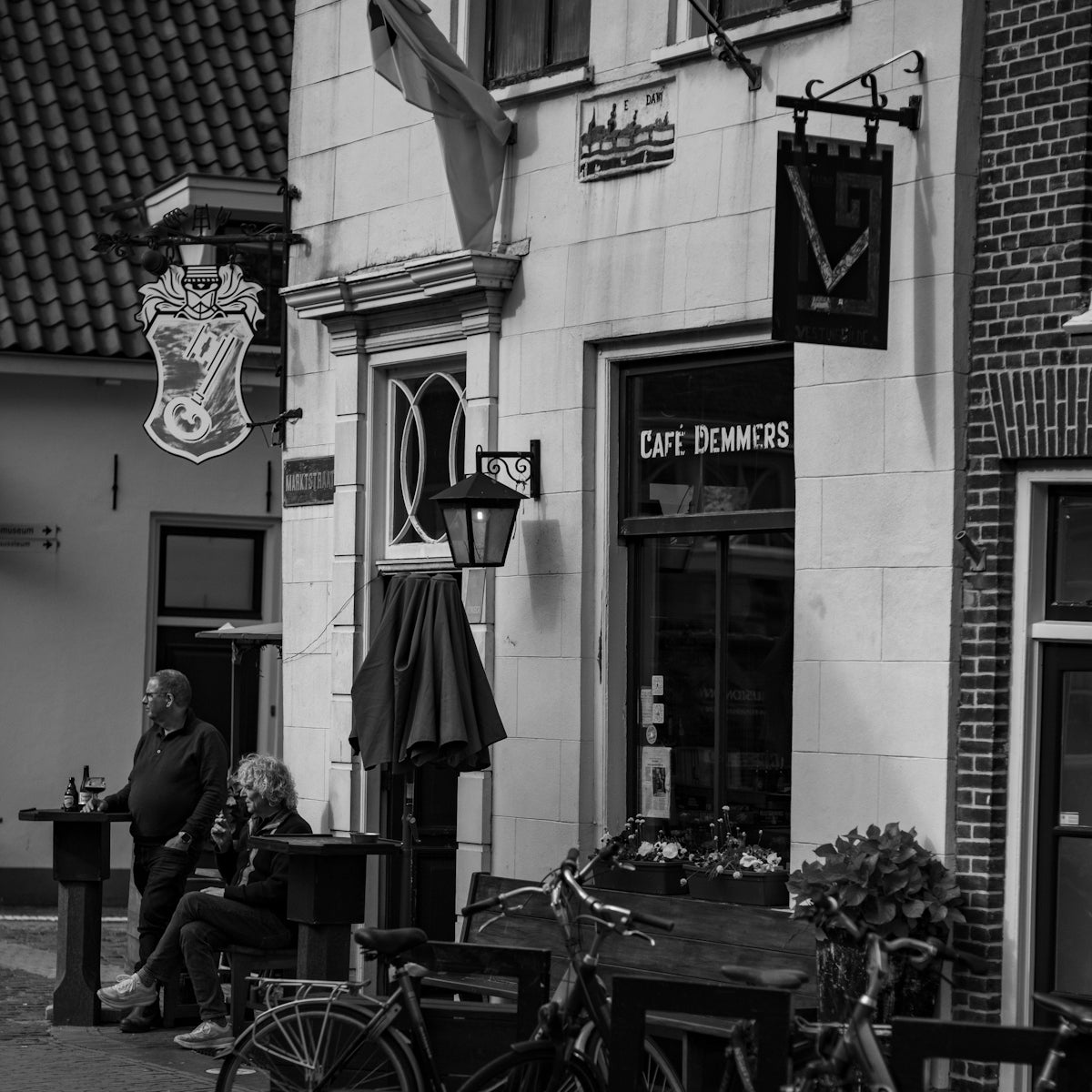 a black and white photo of people sitting outside of a restaurant