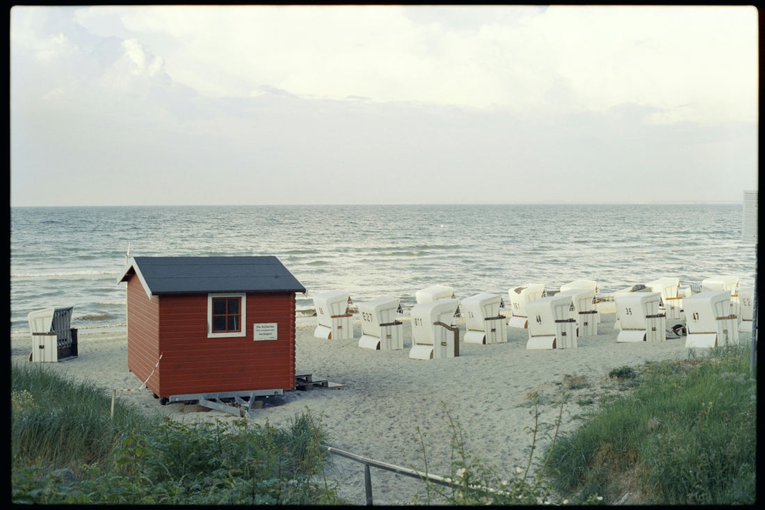 A small red house sitting on top of a sandy beach