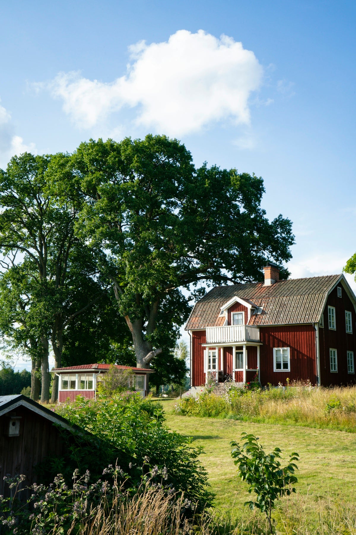 A red house sitting on top of a lush green field