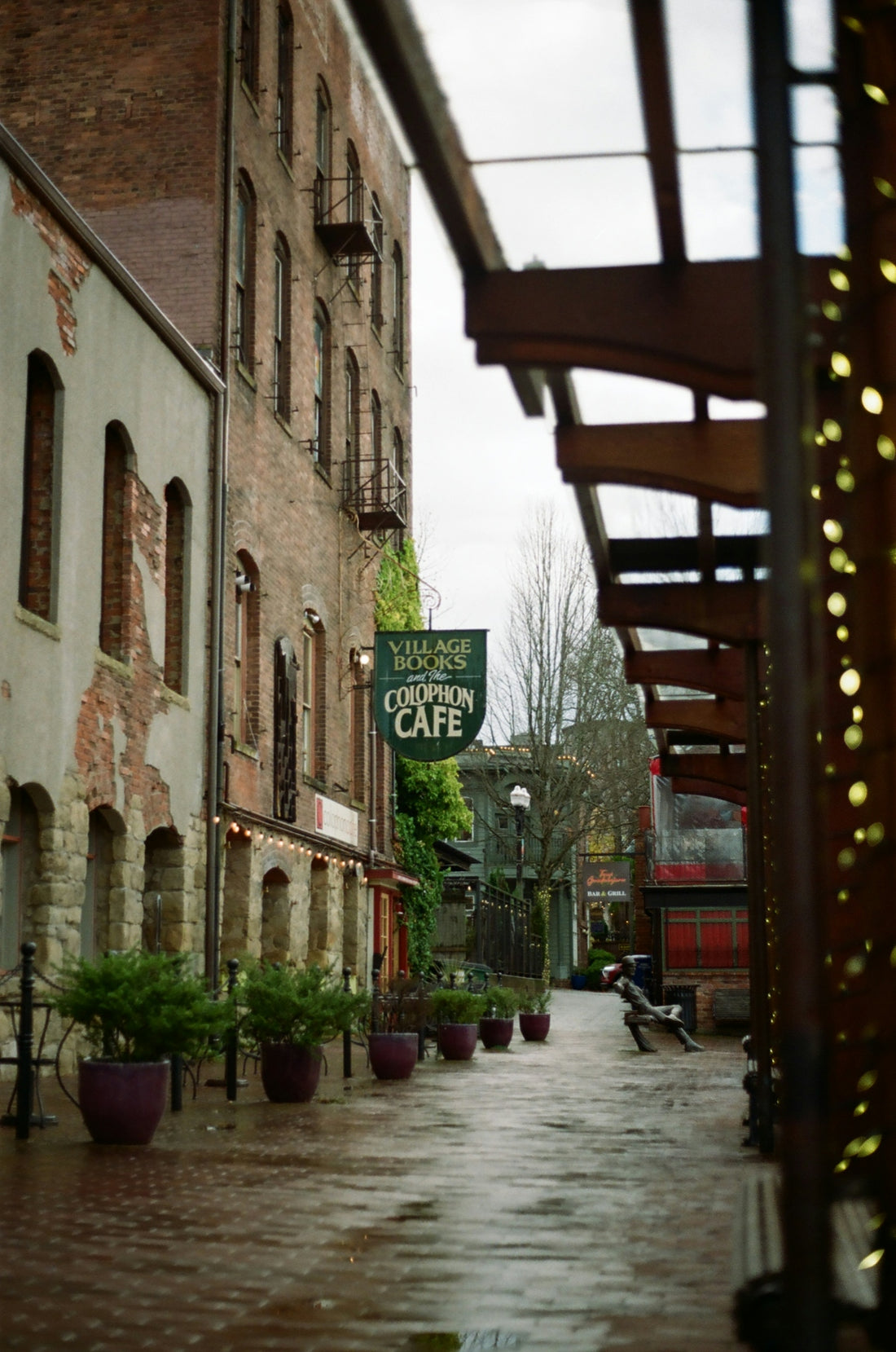 A brick alleyway with a sign for Village Books and the Colophon Cafe
