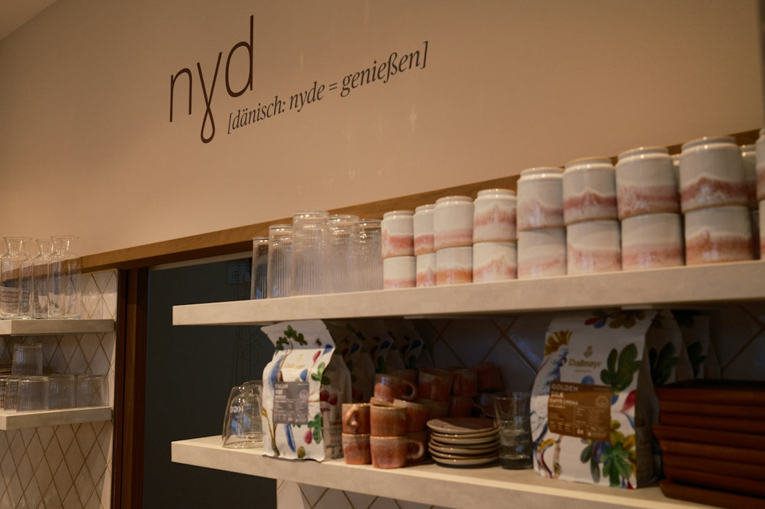 Shelves with ceramic mugs, glasses, and coffee bags in a cafe